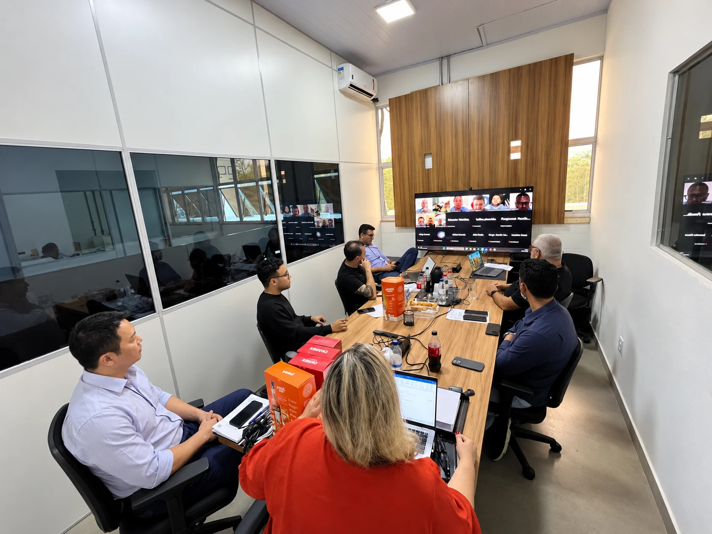 Reunião presencial e por vídeo, com materiais Campari sobre a mesa.